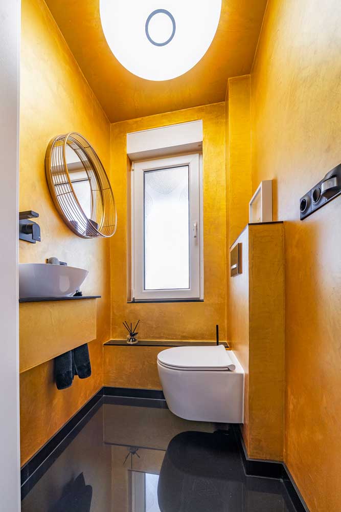 Blick ins Bad mit glodfarbener Wandbeschichtung